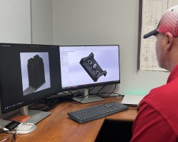 A man sitting at a desk with two computer monitors, efficiently managing various services.